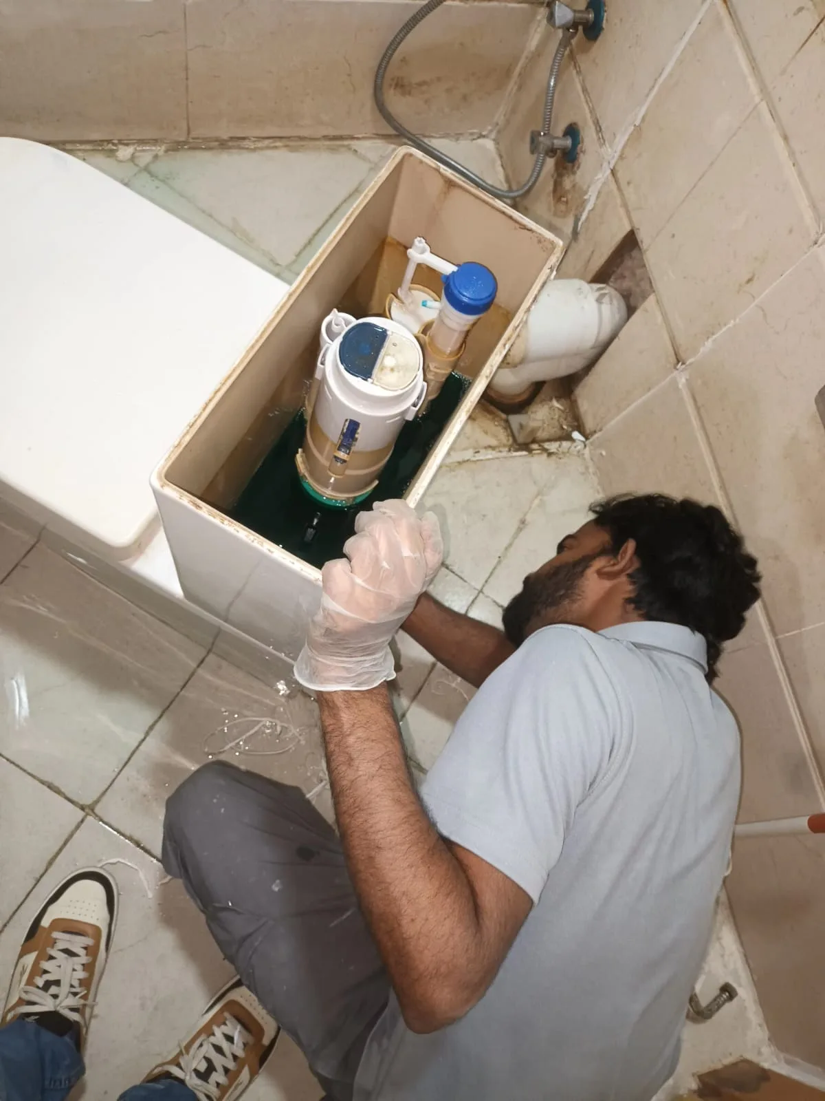 Technician carrying out bathroom plumbing work beside a toilet in Dubai