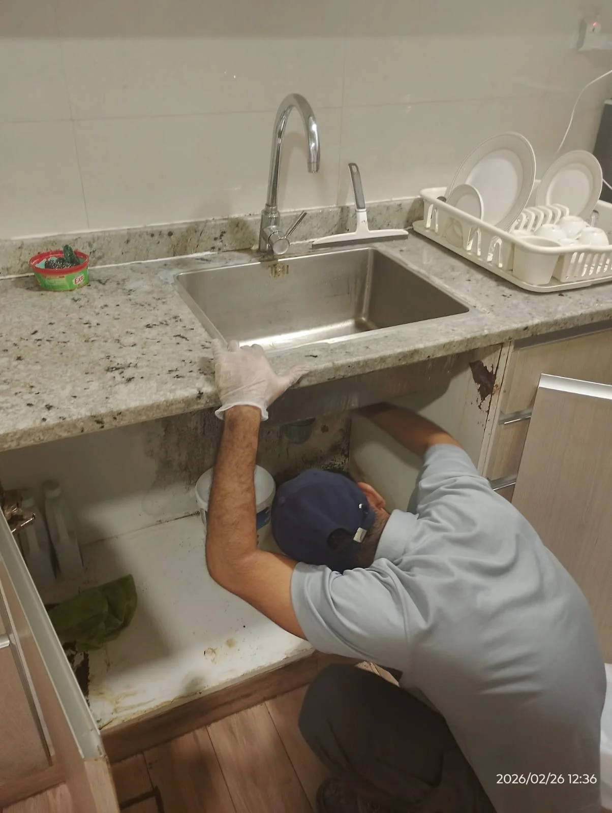 Plumber working beneath a kitchen sink in a Dubai home